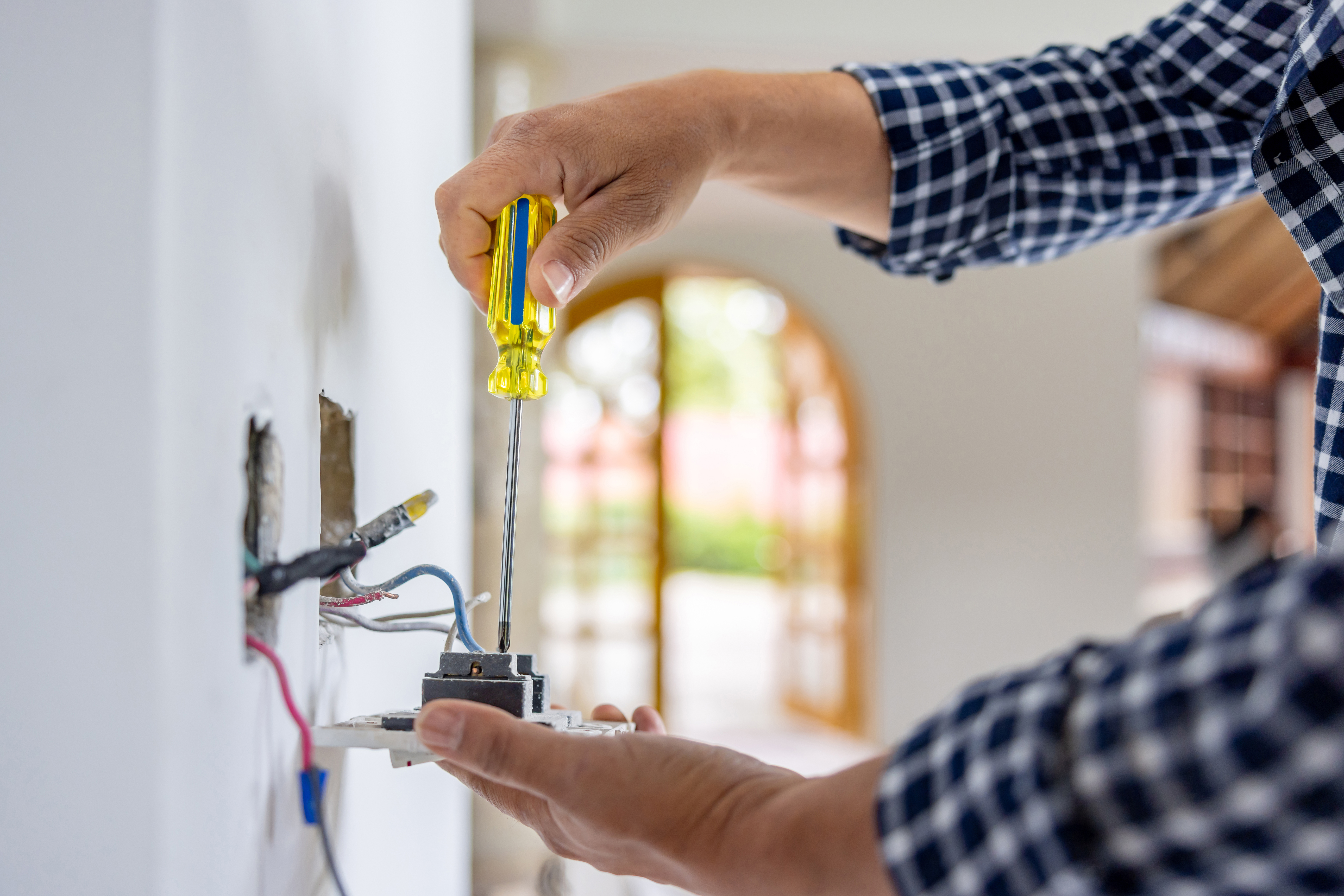 A person using a screwdriver to fix an outlet